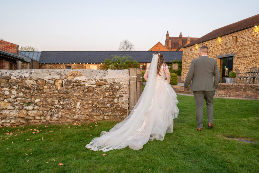 Bride and groom walking away hand in through a gate at Dodford Manor